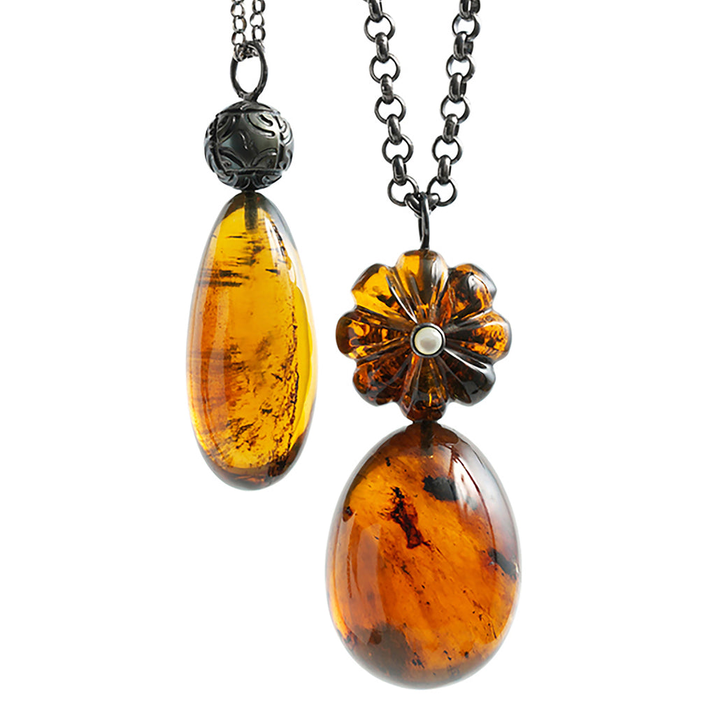 Honey Rush necklaces: Drop shaped Dominican amber pendant with a tattooed Tahitian pearl on blackened cable silver necklace. Egg shaped Dominican amber and flower pendant on on blackened cable silver necklace.